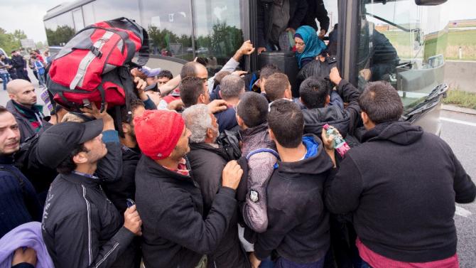 Migrants struggle to board a bus sent to pick them up on the closed highway A4 towards Vienna at the Austrian side of the border between Hungary and Austria on September 11, 2015 near Nickelsdorf, Austria
