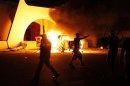 Demonstrators carrying guns celebrate after burning a car they say was full of ammunition as they stormed the headquarters of the Islamist Ansar al-Sharia militia group in Benghazi