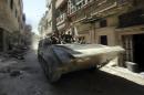 Soldiers of the Syrian government forces patrol on a tank in a devastated street on July 31, 2013 in Syrian city of Homs