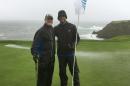 PGA Tour veteran Jerry Kelly, left, and Green Bay quarterback Aaron Rodgers pose on the 8th green at Pebble Beach, Calif., on Tuesday, Feb. 7, 2017, while playing in 40 mph wind and rain. Only at Pebble Beach are players willing to go out in such miserable conditions. (AP Photo/Doug Ferguson)