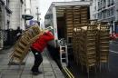 A man loads a van with stacks of gold painted chairs outside a hotel in London