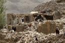 People stand on the rubble of houses destroyed by an air strike in Okash village near Sanaa