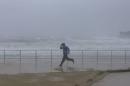 A man runs past heavy seas as sand is blown by heavy winds inland at Sydney's Bondi Beach