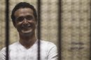 Egyptian activist Ahmed Douma smiles from behind bars during his trial at the New Cairo court, on the outskirts of Cairo