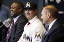 Pitcher Wei-Yin Chen, center, smiles as he sits with Miami Marlins president of operations Michael Hill, left, and agent Scott Boras, right, during a news conference, Tuesday, Jan. 19, 2016, in Miami. The left-handed pitcher finalized an $80 million, five-year contract. (AP Photo/Lynne Sladky)