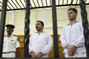 FILE - In this Saturday, Sept. 24, 2011 file photo, policemen Awad Ismail, center, and Amin Mahmoud Salah, right, defendants in the beating death of Khaled Said, stand trial in a courtroom in Alexandria, Egypt. An Egyptian judge on Saturday, June 1, 2013 released from jail two policemen who were convicted of beating a young man to death in a killing that helped inspire the country's 2011 uprising. The move came after an appeals court earlier threw out the policemen's conviction and ordered a retrial. (AP Photo/Tarek Fawzy, File)