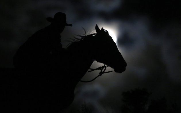 Wrangler Nate Cummins rides by moonlight, the night before the