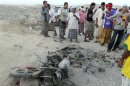 People gather around a motorcycle destroyed in a drone strike near al-Sheher town of Yemen's eastern region of Hadramout