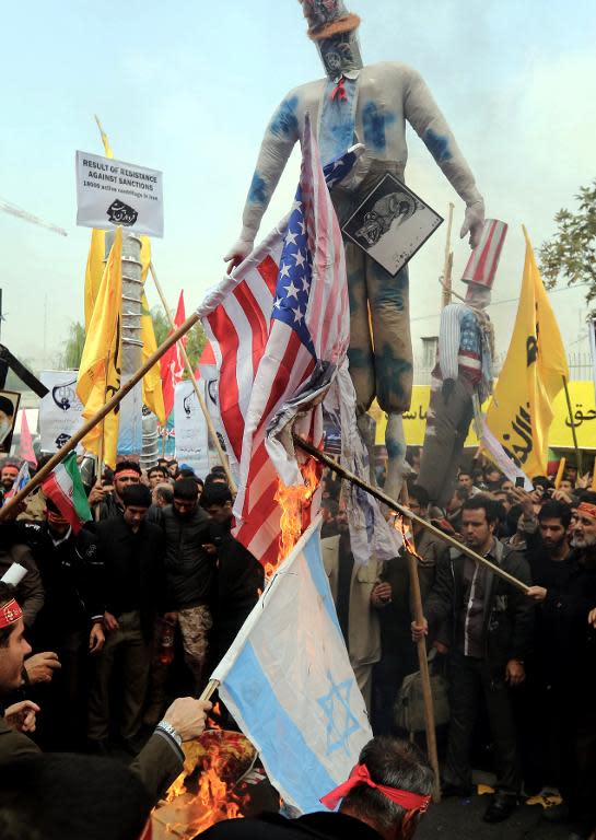 People burn US and Israeli flags outside the former US embassy in Tehran on November 4, 2013