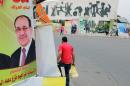 FILE - In this file photo taken on April 27, 2014 a man passes by a campaign poster of Iraqi Prime Minister Nouri al-Maliki in Baghdad, Iraq. If Iraqi Prime Minister Nouri al-Maliki wins a third four-year term in parliamentary elections Wednesday, he is likely to rely on a narrow sectarian Shiite base, only fueling divisions as Iraq slides deeper into bloody Shiite-Sunni hatreds. (AP Photo/Karim Kadim, File)