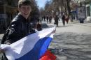 A local teenager waves with Russian flag in a street in Simferopol, Ukraine, on Monday, March 17, 2014. Ukraine's Crimean peninsula declared itself independent Monday after its residents voted overwhelmingly to secede and join Russia, while the United States and the European Union slapped sanctions against some of those who promoted the divisive referendum. (AP Photo/Ivan Sekretarev)