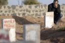 A Kurdish man mourns next to gravestones of Kurdish fighters killed during clashes against Islamic State in the Syrian town of Kobani