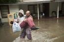 Charles Davidson helps his neighbor Santonio Coleman, 11, from his flooded home in the Kelly Ave. Basin area of Pensacola