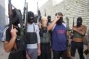 Masked Sunni gunmen pose for a photo during a patrol outside the city of Falluja