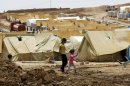Syrian-Kurdish refugee children walk past tents in the Domiz refugee camp in northern Iraq