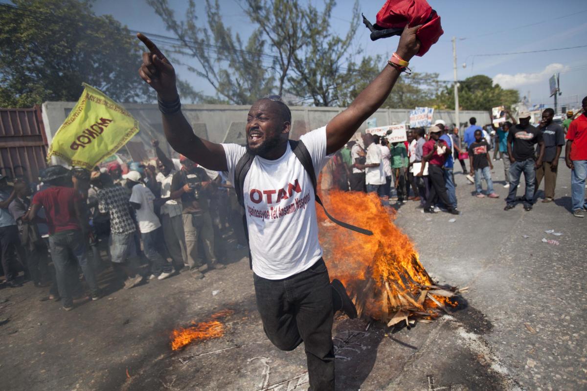 In this Friday, Jan. 23, 2015 photo, a demonstrator uses wood, gas, fire and salt to call forth a spirit to ask for protection, in a voodoo ceremony before the start of a protest demanding the resignation of President Michel Martelly in Port-au-Prince, Haiti. The hardline opposition to Martelly has promised a wave of intensified street protests to try and pressure him from office. Martelly took office in 2011 and is due to leave next year. (AP Photo/Dieu Nalio Chery)