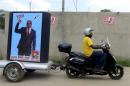 A supporter of the ruling Frelimo party rides a motorcycle with an election poster in tow in the capital Maputo