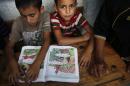 Palestinian boys read at a United Nations school where dozens of families have sought refuge after fleeing their homes following heavy Israeli forces' strikes in Beit Hanoun, northern Gaza Strip, Saturday, July 19, 2014. (AP Photo/Lefteris Pitarakis)