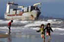 Varios niños corren en la playa de El Saler, en Valencia, cerca de los buques varados BSLE Sunrise y Celia. EFE/Archivo