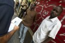 Israeli immigration officers check an African migrant in Tel Aviv on June 12, 2012