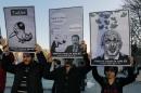 Members of the Turkish Youth Union hold cartoons depicting Turkey's Prime Minister Recep Tayyip Erdogan during a protest against a ban on Twitter, in Ankara, Turkey, Friday, March 21, 2014. Turkey's attempt to block access to Twitter appeared to backfire on Friday with many tech-savvy users circumventing the ban and suspicions growing that the prime minister was using court orders to suppress corruption allegations against him and his government. Cartoon in center reads: Erdogan, left, to his Ankara Mayor Melih Gokcek " we will rip out the roots of Twitter." Gokcek: "don't say it." (AP Photo/Burhan Ozbilici)
