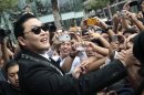 FILE - In this Nov. 28, 2012 file photo, South Korean rapper PSY, who sings the popular "Gangnam Style," greets Thai fans after a press conference in Bangkok, Thailand. As "Gangnam Style" gallops toward 1 billion views on YouTube, the first Asian pop artist to capture a massive global audience has gotten richer click by click. So too has his agent and his grandmother. But the money from music sales isn't flowing in from the rapper's homeland South Korea or elsewhere in Asia. With one song, 34-year-old Park Jae-sang — better known as PSY — is set to become a millionaire from YouTube ads and iTunes downloads, underlining a shift in how money is being made in the music business. (AP Photo/Sakchai Lalit, File)