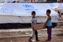 Young Iraqis who fled violence carry a parcel of food at the Bahrka camp on August 20, 2014