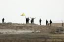 In this photo taken from the Turkish side of the border between Turkey and Syria, in Akcakale, southeastern Turkey, Kurdish fighters with the Kurdish People's Protection Units, or YPG, wave their yellow triangular flag in the outskirts of Tal Abyad, Syria, Monday, June 15, 2015. (AP Photo/Lefteris Pitarakis)