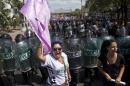 Women from various women's rights organizations shout slogans against Daniel Ortega's government as police block the road to keep them from crossing paths with pro-government sympathizers, top, in Managua, Nicaragua, Sunday, March 8, 2015. The anti-government march was held to commemorate International Women's Day. (AP Photo/Esteban Felix)