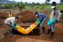 Volunteers in protective suits bury the body of a person who died from Ebola in Waterloo on October 7, 2014