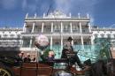 Passengers wave to journalists from a traditional Fiaker horse-carriage as they pass Palais Coburg hotel in Vienna