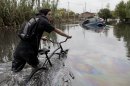 A man pushes his bike through a flooded street in La Plata, in Argentina's Buenos Aires province, Wednesday, April 3, 2013. At least 35 people were killed by flooding overnight in Argentina's Buenos Aires province, the governor said Wednesday, bringing the overall death toll from days of torrential rains to at least 41 and leaving large stretches of the provincial capital under water. (AP Photo/Natacha Pisarenko)
