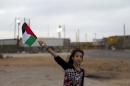A Palestinian girl from the Israeli occupied West Bank waves the national flag as she and others wait close to the military prison of Ofer for the release of Palestinian prisoners on August 13, 2013