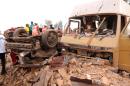 Emergency response workers walk by destroyed vehicles at the site of a car bomb blast where football fans were watching the final of the UEFA Champions League match the night before, at a viewing centre in the central Nigerian city of Jos, on May 25