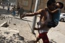 A man carries a boy as he runs with other civilians to take cover after what activists said was a missile strike by Syrian Air Force fighter jets loyal to President Bashar al-Assad, in Raqqa province