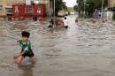Iraqi boys make their way through a flooded street after heavy rain fell in Baghdad, Iraq, Thursday, Oct. 29, 2015. Rain storms began late day Wednesday and continued through the morning Thursday, dumping heavy rain on the Iraqi capital and across the country. The Iraqi government declared Thursday a holiday to ease the burden on people who may otherwise struggle to get to work. (AP Photo/Karim Kadim)