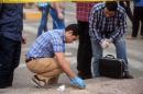 Egyptian forensics inspect the site following a bomb attack targeting a security checkpoint in central Cairo on April 15, 2014