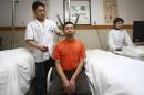 A doctor adjusts a device attached to a patient's neck during a traditional Chinese medical treatment to cure cervical spondylosis at a hospital in Suining