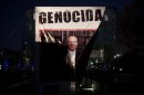 A banner with a defaced picture of Mexico's President Felipe Calderon that reads in Spanish "Genocide" hangs on the covering of a stairway where it was placed by demonstrators protesting violence in Mexico City, Wednesday, Nov. 28, 2012. Mexico will inaugurate a new president on Saturday, after Calderon's six-year militarized offensive against drug cartels. (AP Photo/Alexandre Meneghini)