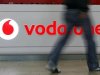 A customer walks past the Vodafone logo in a shopping mall in Prague