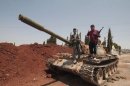 Syrian rebel fighters stand on top of a government tank captured two days earlier at a checkpoint