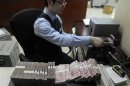 An employee counts 100 Chinese yuan banknotes at a bank in Hefei