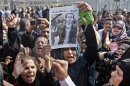 Egyptian relatives of Mohammed el-Gindy, a 28-year-old activist, who died early Monday of wounds sustained during clashes last Friday near the presidential palace, display his picture as they shout anti-president Morsi slogans during his funeral procession in Tahrir Square, Cairo, Egypt, Monday, Feb. 4, 2013. More than 60 people have died in recent protests across Egypt that began on Thursday, Jan. 24, 2013, the eve of the second anniversary of the start of the uprising that toppled autocrat Hosni Mubarak. Arabic reads "my name is Mohammed and I did not deserve to die this way." (AP Photo/Amr Nabil)