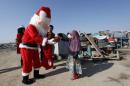 A volunteer wearing a Santa Claus costume distributes presents to children at a poor community in Najaf