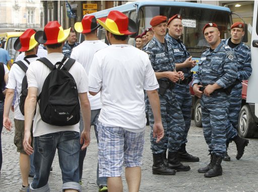 German fans walk past Ukrainian riot police in central Lviv
