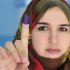 A woman shows her ink-stained finger after casting her vote in the National Congress election, in Benghazi