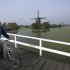 FILE - In this Oct. 11, 2007 file photo a Dutch man rides his bike in front of windmills in Kinderdijk, Netherlands. While tax hikes and budget cuts have led to partisan warfare in the U.S. and widespread strikes in Southern Europe, in 2013 the Netherlands is weathering "austerity" with relative grace. Some say that's because the country is experiencing a renaissance of its famed "Polder Model," a compromise system in which a centrist government works with labor unions and employers' associations to ensure the burden of painful economic reforms are shared across society. Poldering is deeply rooted in Dutch society: Historically the population had to cooperate to maintain a costly system of windmills and dikes to prevent floods and turn marshes into dry farmland known as polders. (AP Photo/ Evert-Jan Daniels, File)