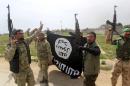 Members of the Iraqi paramilitary Popular Mobilisation units celebrate with a flag of the Islamic State (IS) group after retaking the village of Albu Ajil, near the city of Tikrit, from the jihadist group, on March 9, 2015
