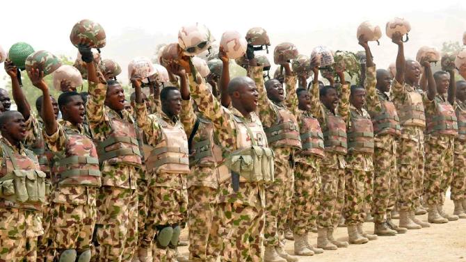 Handout picture by State House Photo on February 26, 2015, shows soldiers fighting Boko Haram Islamists raising helmets to salute Nigerian President Goodluck Jonathan on his arrival in the town of Mubi, recently recaptured from insurgents