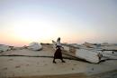 An armed pirate walking past skiffs, used to raid ships on the high-seas, at the coastal town of Hobyo, on November 10, 2009